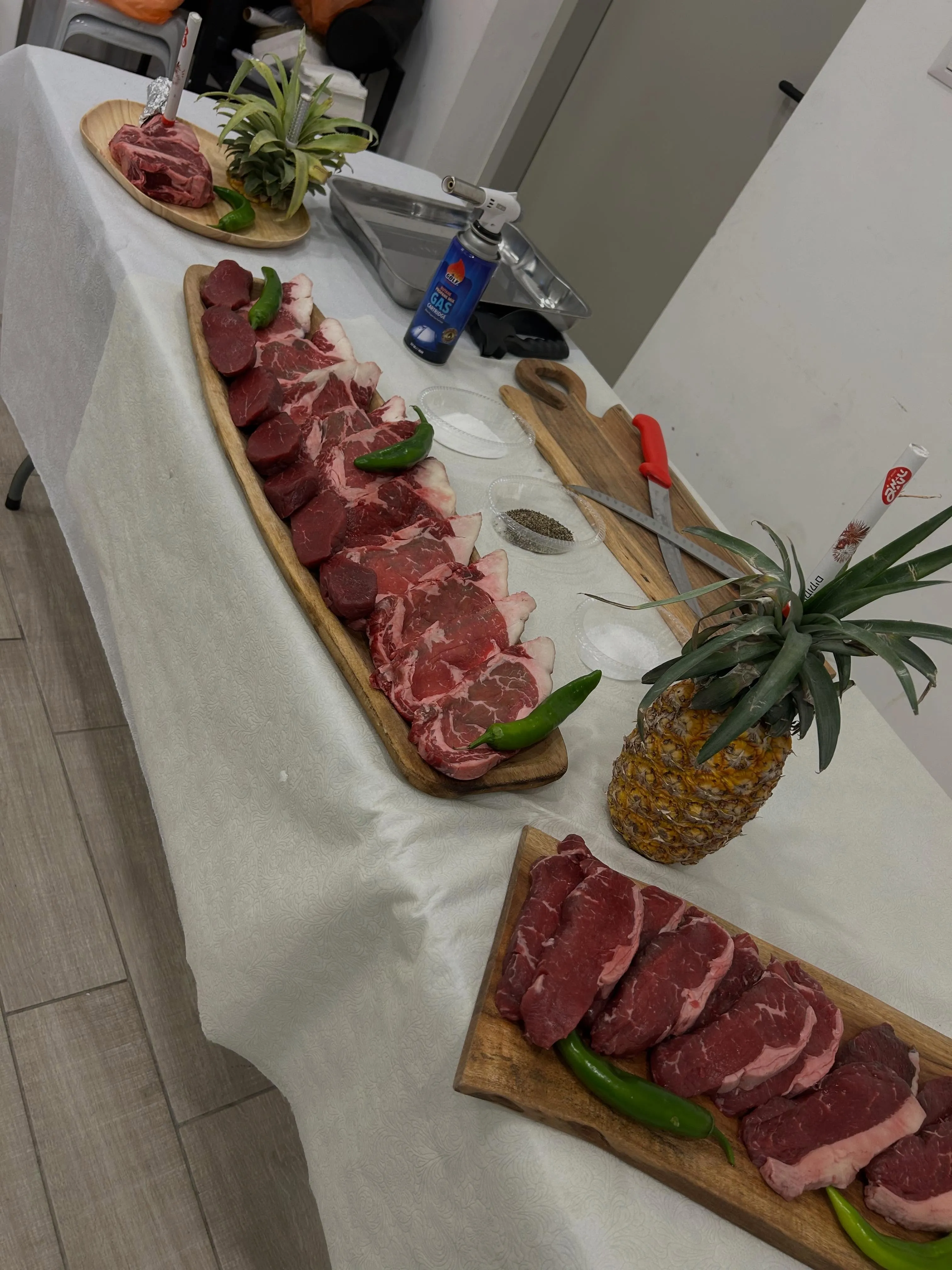 בשרים טריים מסודרים על קרשי עץ ארוכים לפני האירוע: אנטרקוט, פילה ופלפלים חריפים ירוקים